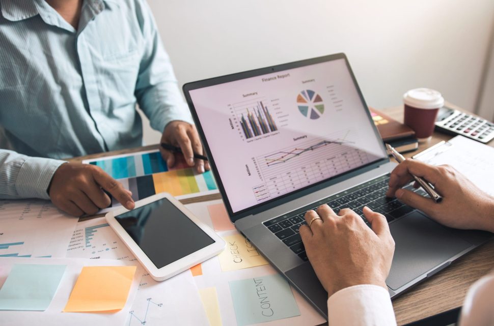 Two business partnership coworkers discussing a financial planning graph and company during a budget meeting in office room.